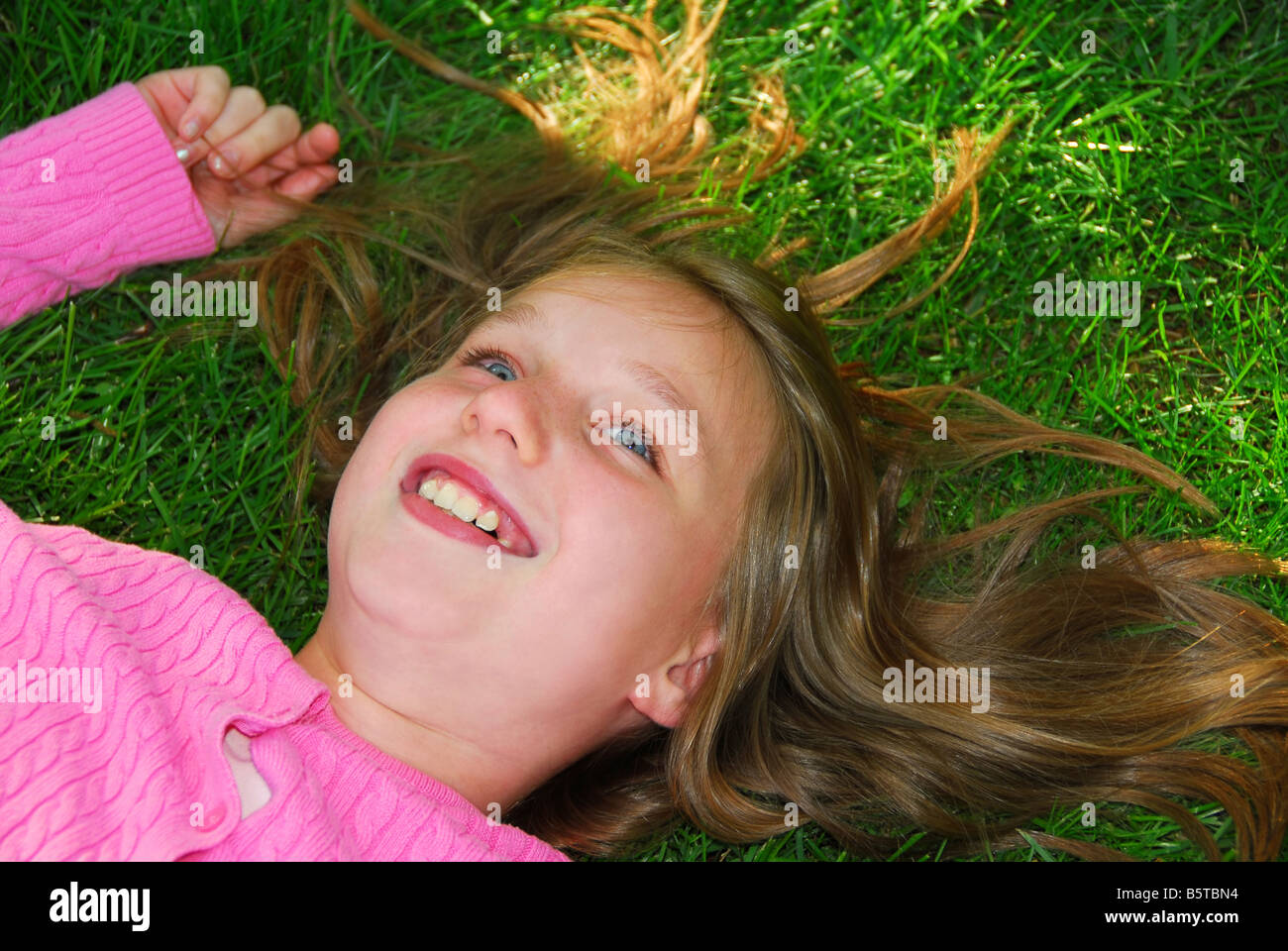 Young girl relaxing on green grass outside Stock Photo - Alamy