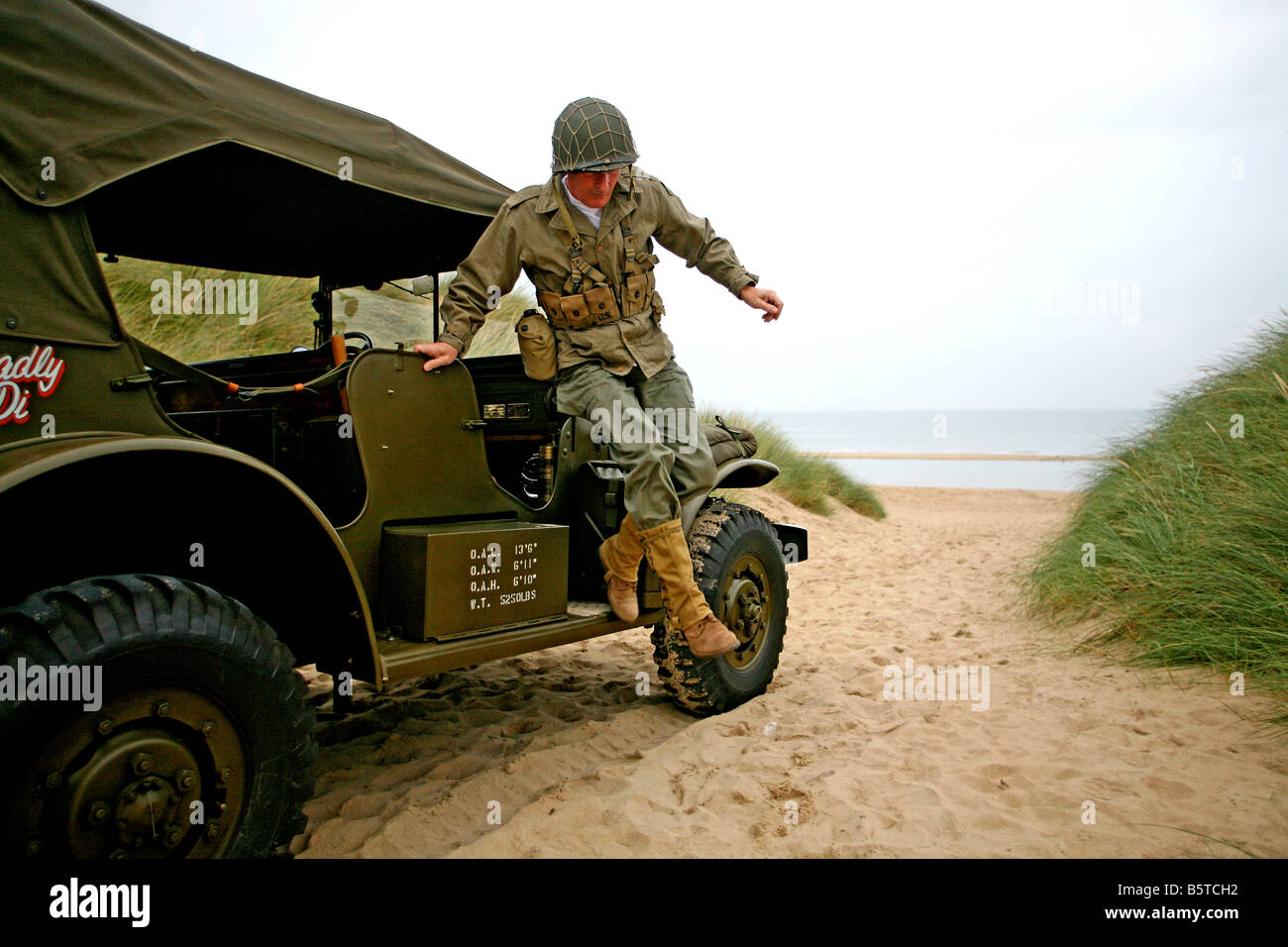 actor dressed as a D-Day  American soldier  jumps down from a Dodge command car on  Utah Beach Normandy ,France Stock Photo