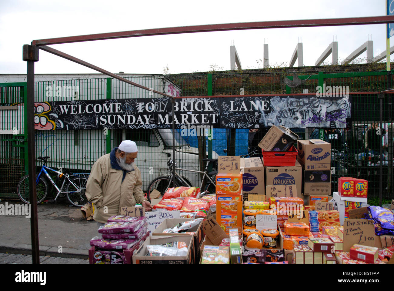 Asian Muslim man inspecting food on Brick Lane Market stall London England Stock Photo