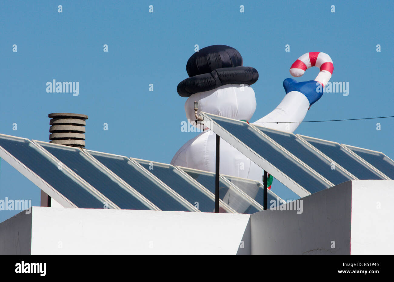 Large inflatable snowman on roof covered in solar panels in spain stock