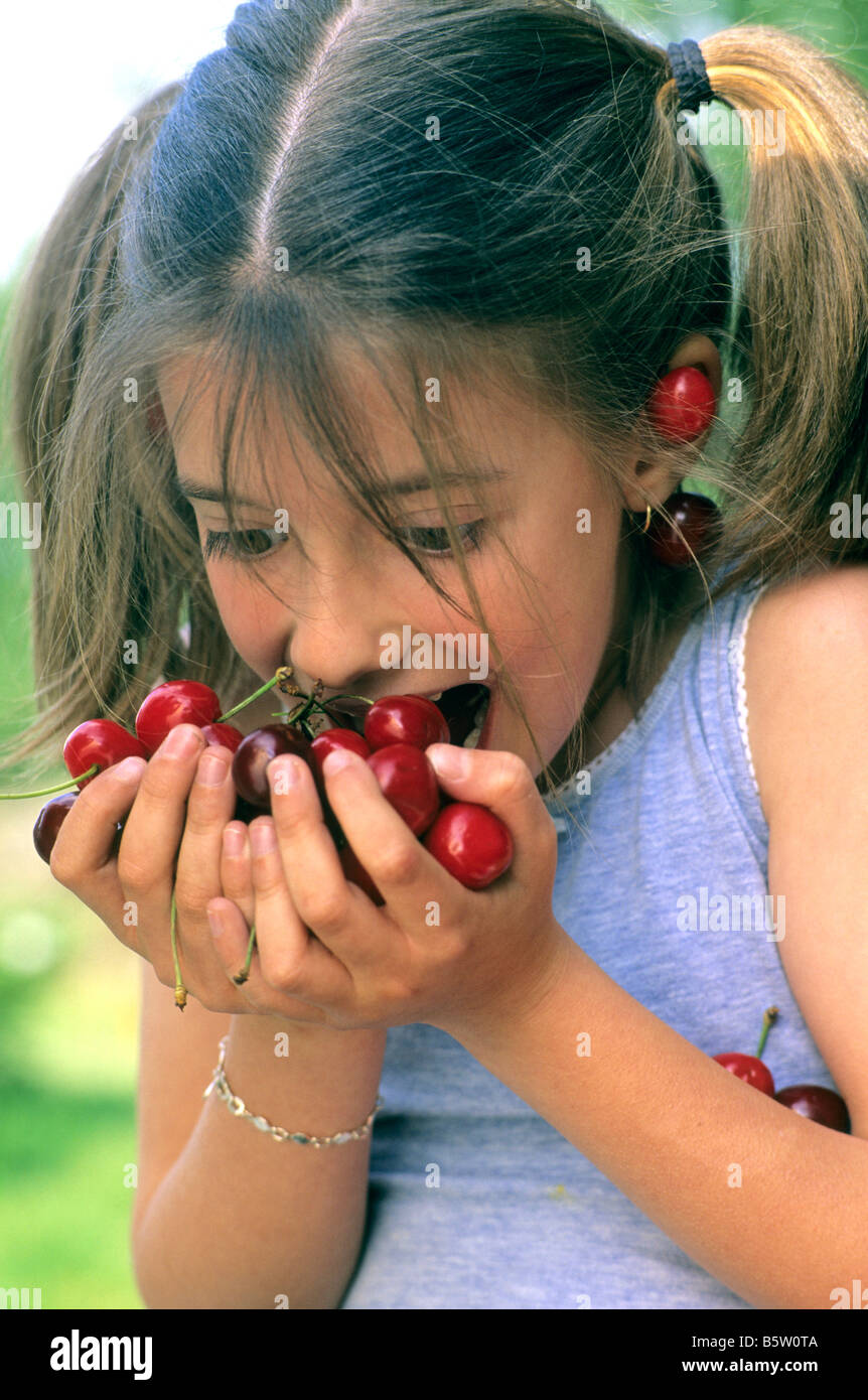 Female child eating fruit close up outdoors in summer Stock Photo