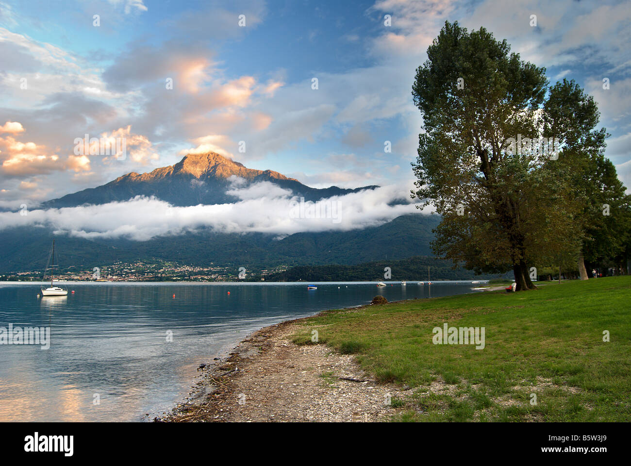 Evening sun hits a mountain peak behind Domaso on the shores of Lake Como in Lombardy, Italy. Stock Photo