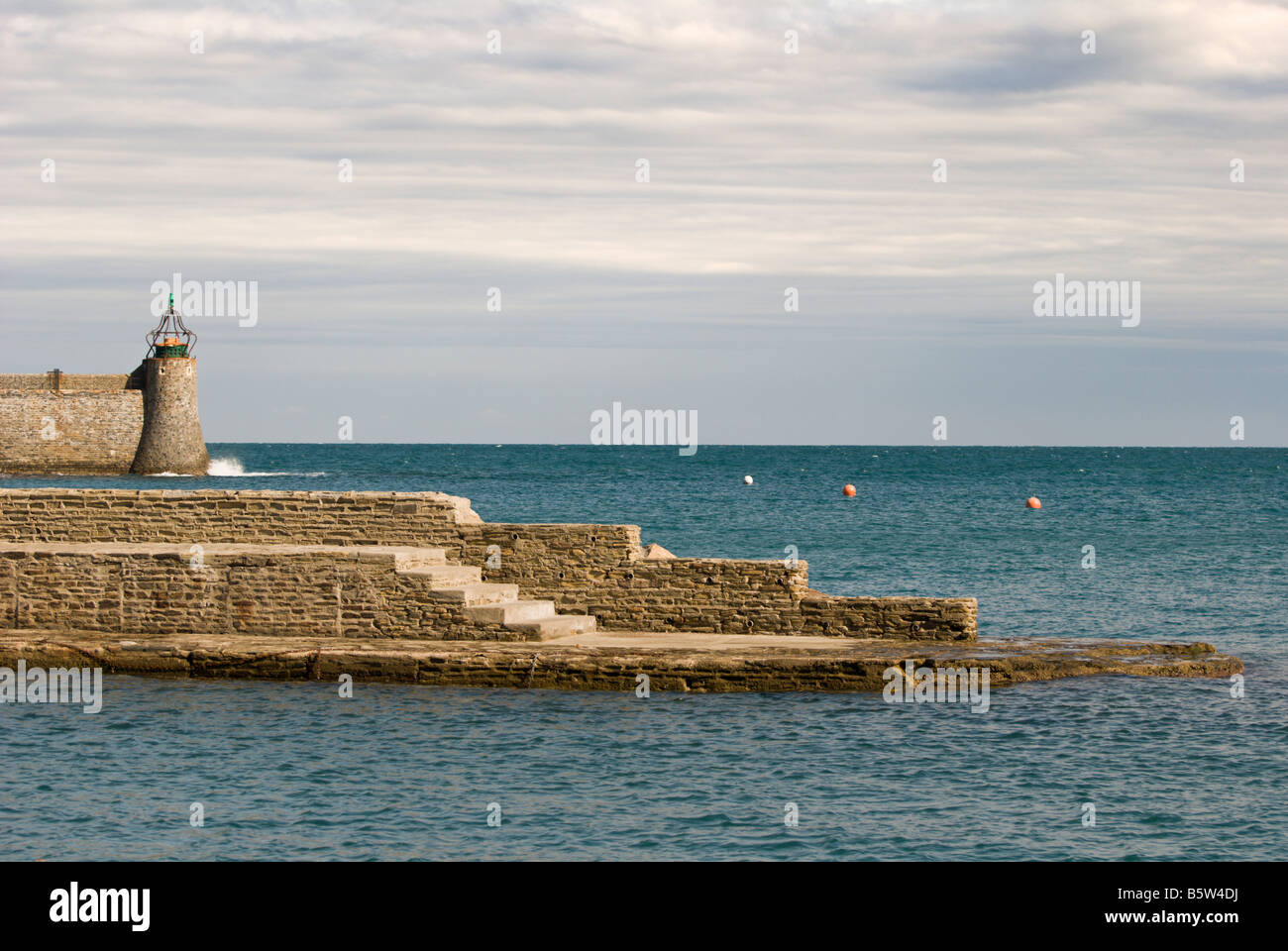 Sea wall and lighthouse at the entrance to the fishing harbour at Collioure, in the south of France. Stock Photo