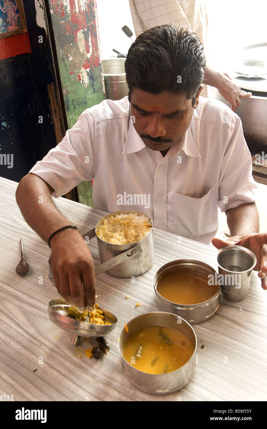 Man eating rice with sambar and vegetable curry from his tiffin box (lunch box) in Pondicherry