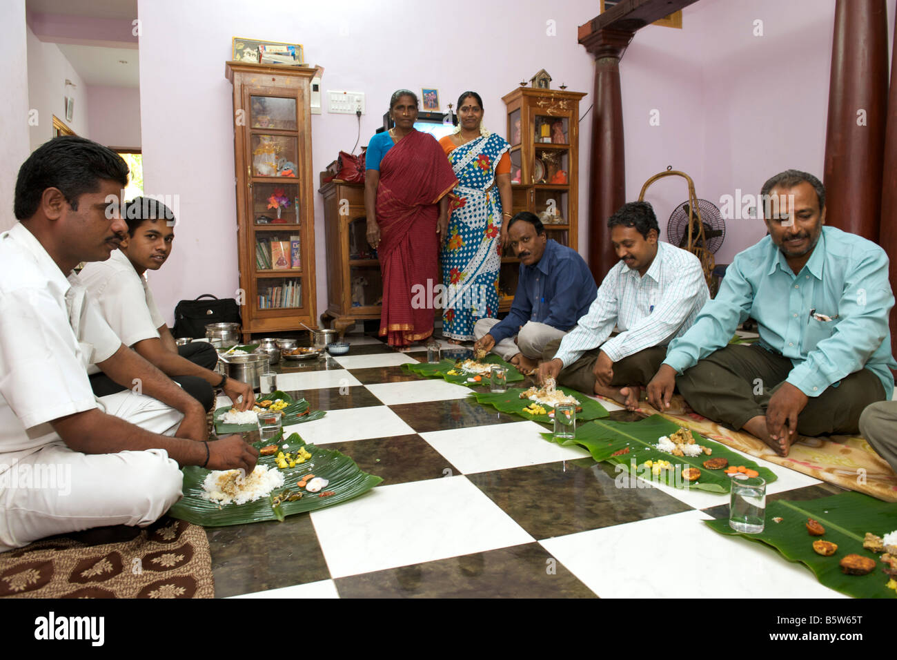 Group of Indians eating off banana leaves whilst seated on the floor in Pondicherry India. Stock Photo