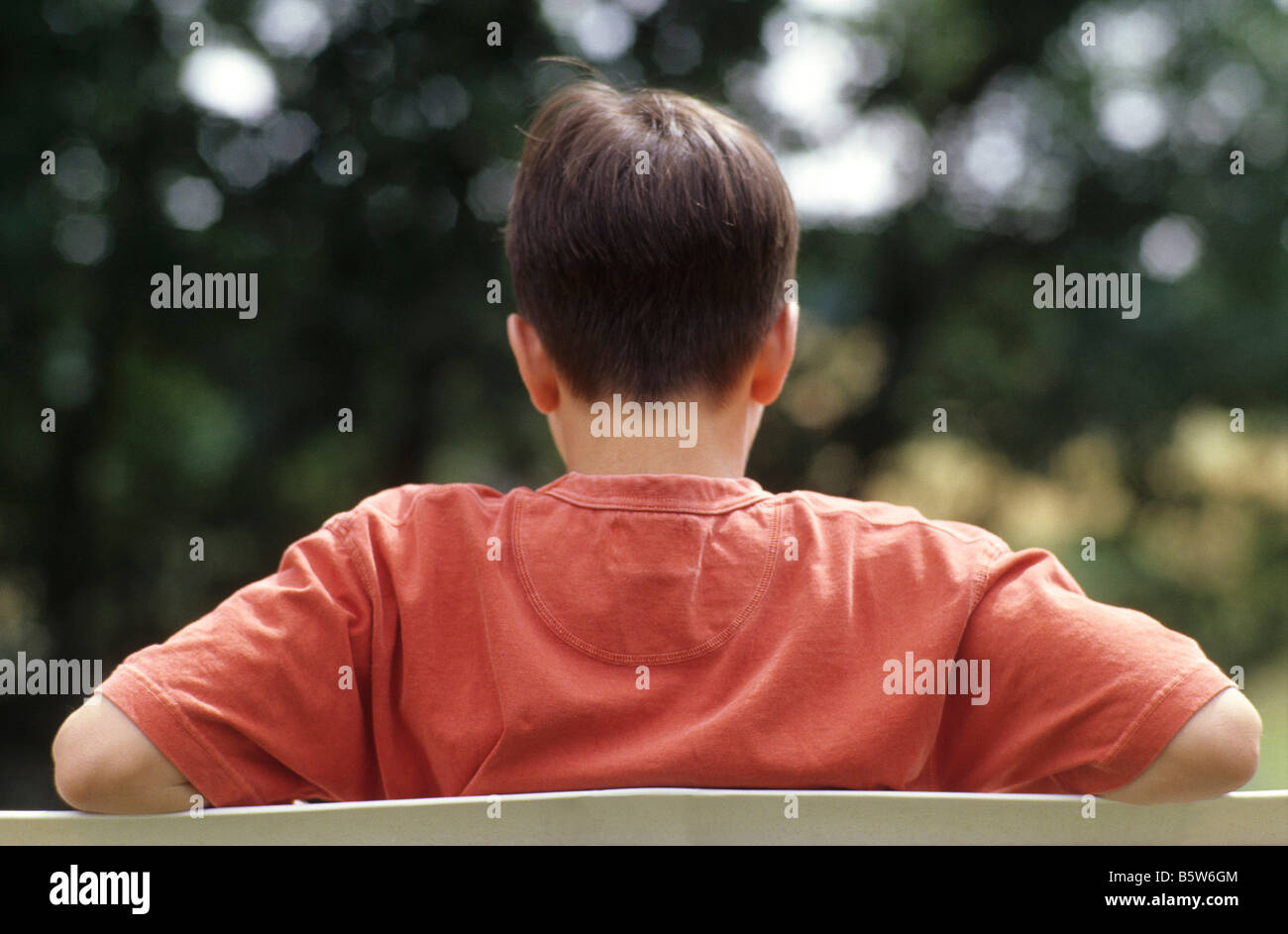 Teenage boy sitting rear view Stock Photo