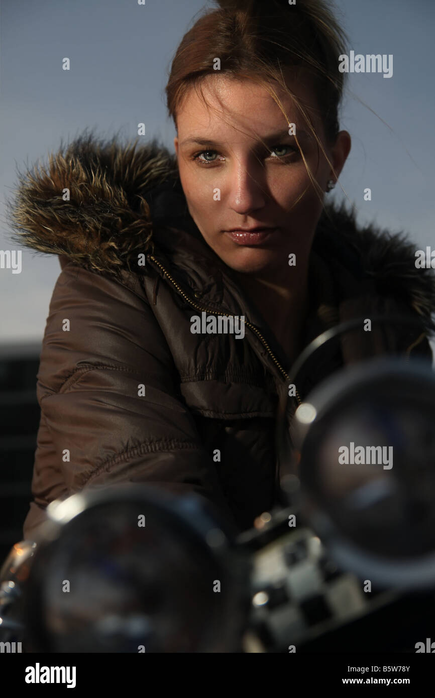 Young woman sitting on her motorcycle dark mood Looking at you Nightshot Stock Photo