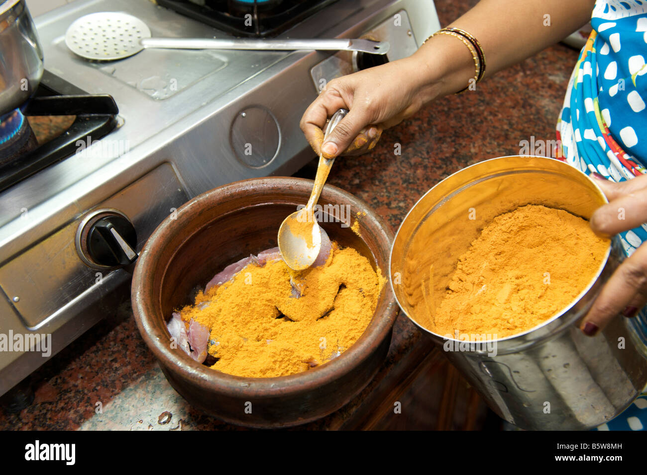 Adding the seasoning of chilli powder, coriander powder, cumin and curry powder to seer fish for a fried fish dish. Stock Photo