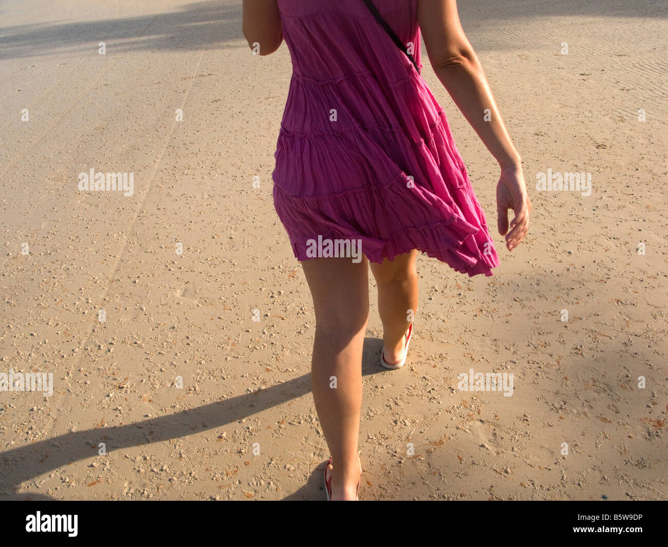 Woman in pink dress walking along the beach Stock Photo - Alamy