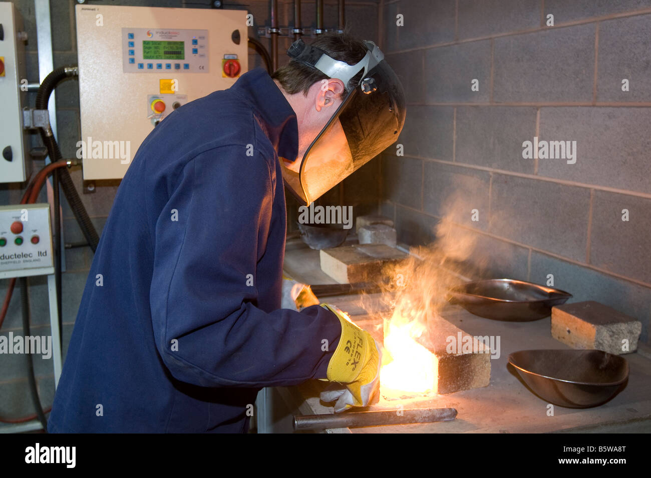 Worker at a steel recycling centre smelting samples in a furnace Stock Photo