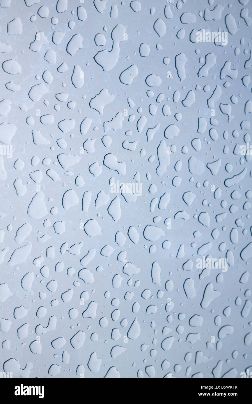 Droplets of water form a pattern on a window on a rainy day. Stock Photo