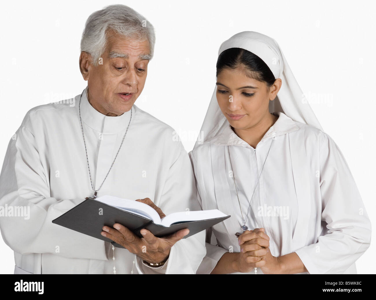 Priest and a nun looking at the Bible Stock Photo - Alamy