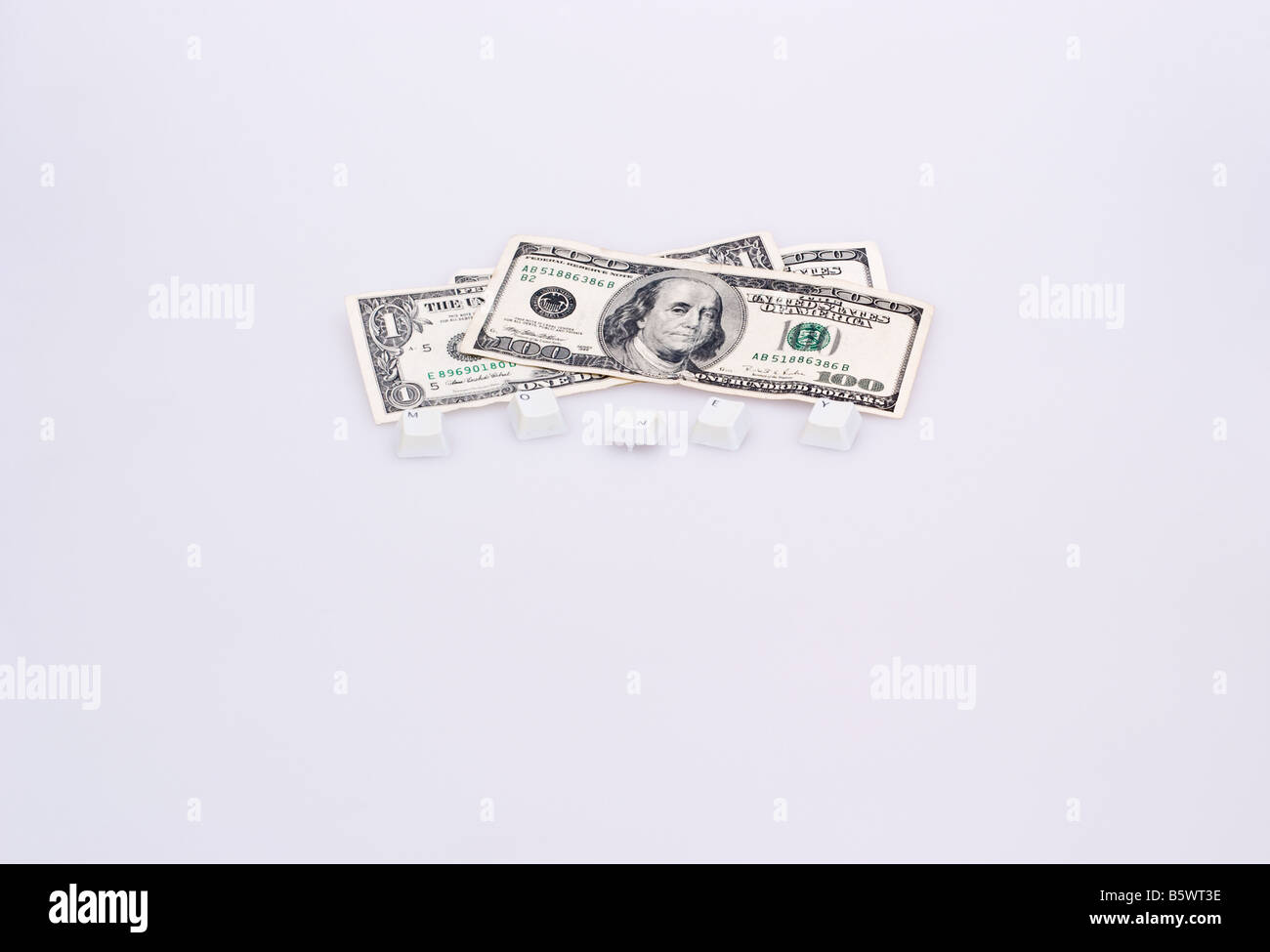 Pile of US currency with computer keys in front spelling the work money Stock Photo