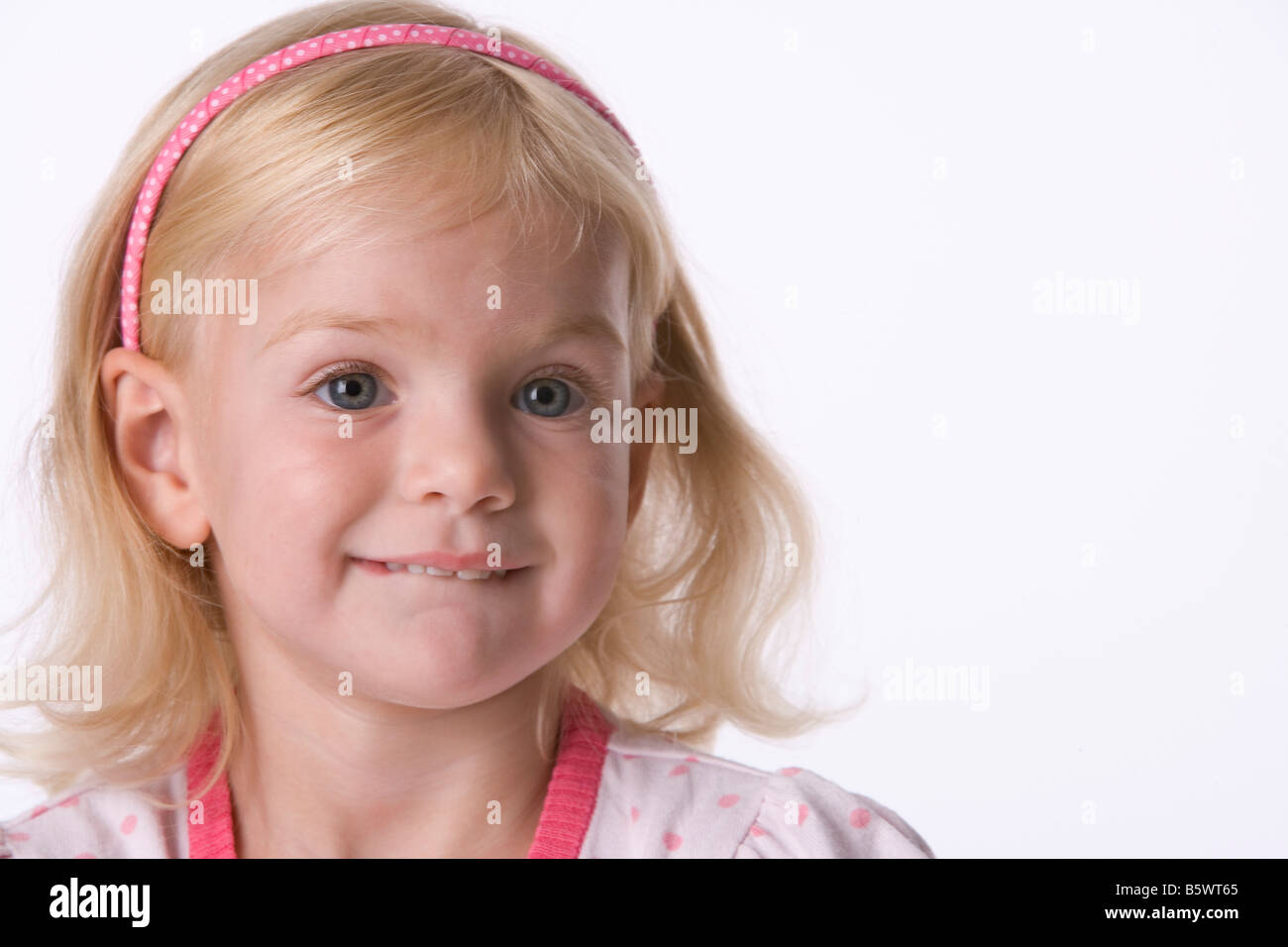 Portrait of a little blond girl biting her lip Stock Photo