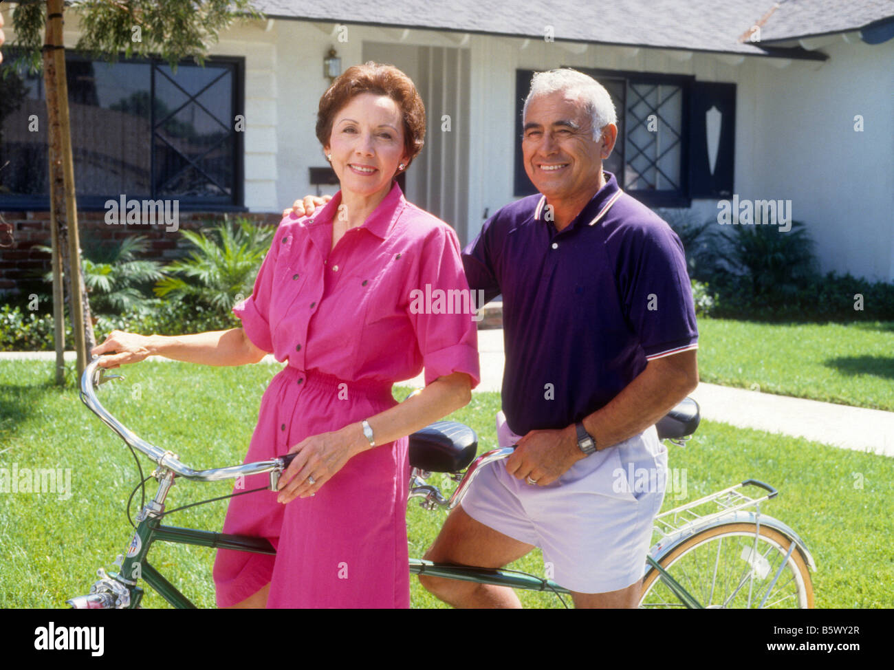 Senior Hispanic couple rides tandem bike Stock Photo
