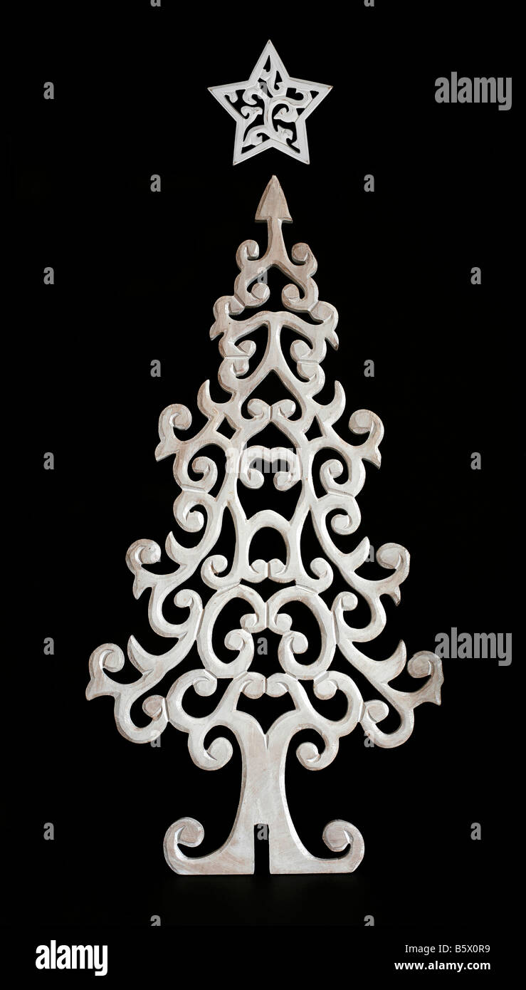 White christmas tree and star carved out of wood on black background ...