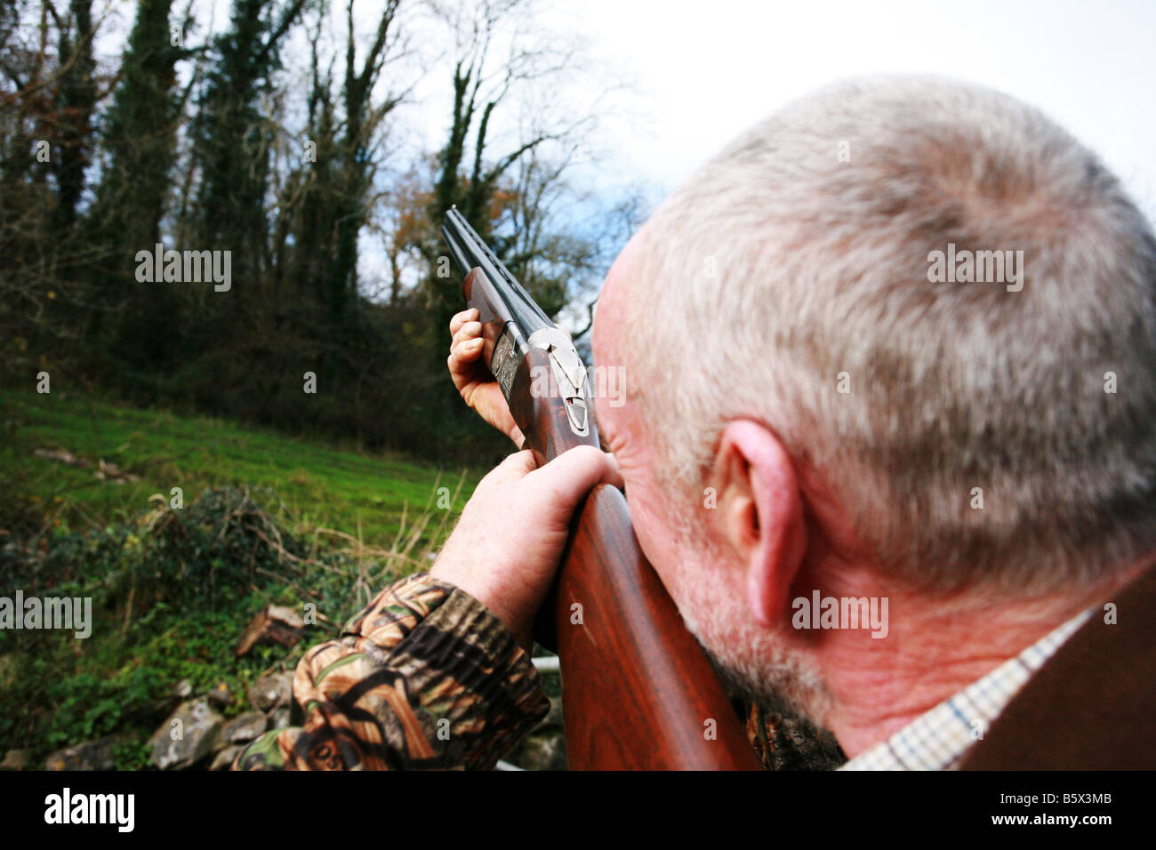 Close up of a stock action 12 gauge shotgun being held in shooting