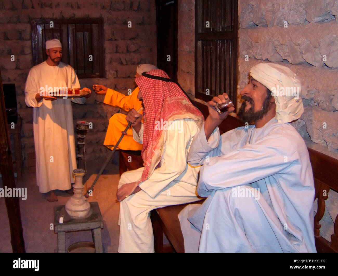 History of VAE arab people drinking tea and smoking Shisha Dubai Museum Dubai United Arab Emirates Stock Photo