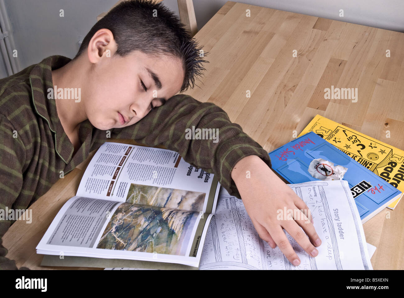 10 YEARS OLD BOY SLEEPING WHILE HE WAS STUDIYING AT HOME BECAUSE OF EXHAUSTION Stock Photo