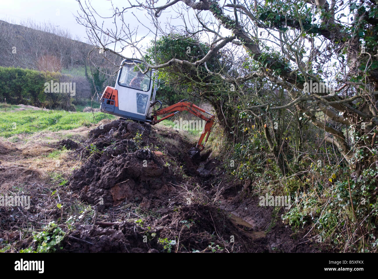 Simon Buttimore digging out a drainage ditch with a mini digger Stock Photo