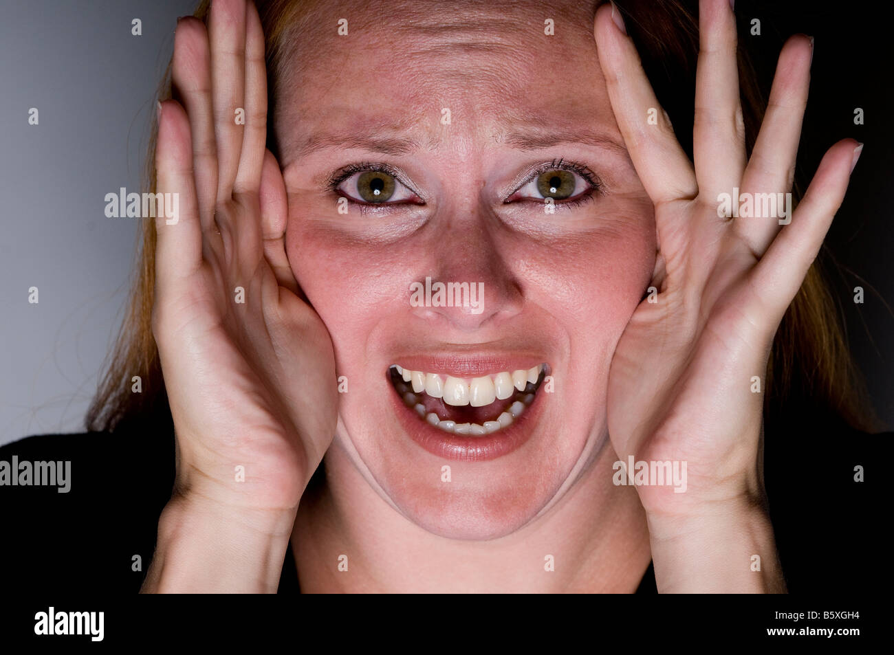 Young woman looking scared through hands stressed. Stock Photo