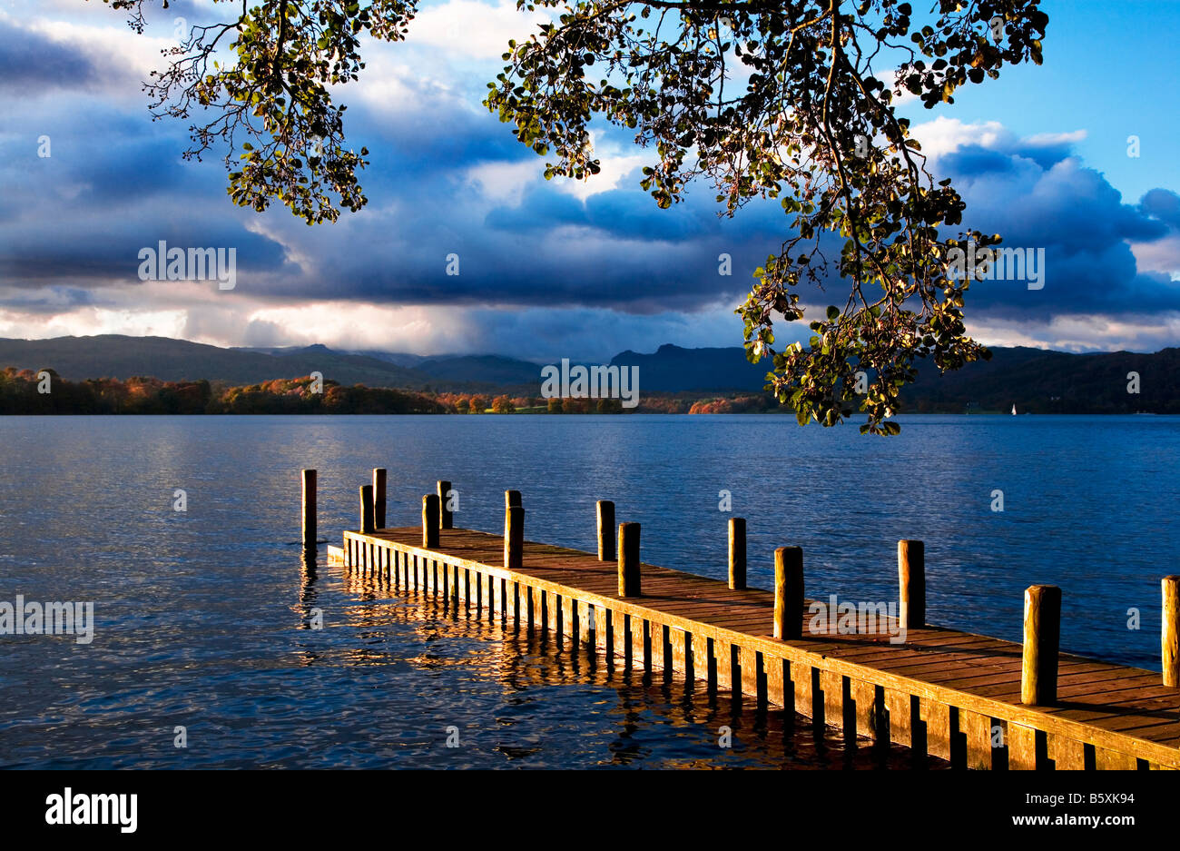 Late afternoon sunshine on jetty, eastern shore Lake Windermere, Langdale Pikes in the distance Lake District Cumbria England UK Stock Photo