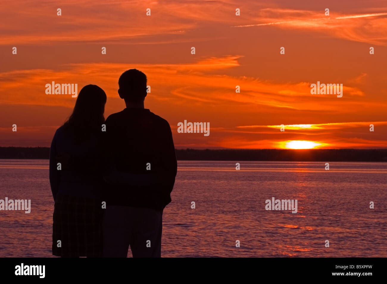 Silhouette of young couple standing on beach at sunset Stock Photo - Alamy