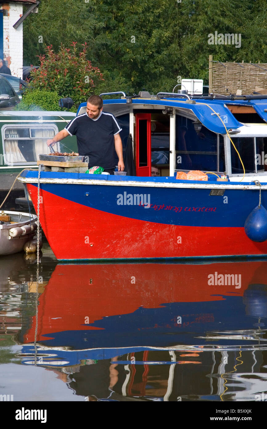 Man cooking on a narrowboat moored in the River Avon at Stratford upon Avon Warwickshire England Stock Photo