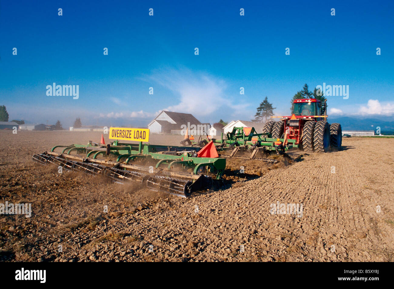 A track tractor pulls a cultivator through the field to help prepare
