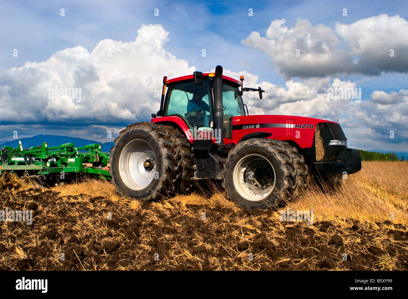 A tractor pulling a disk ripper tills existing field stubble to begin ...