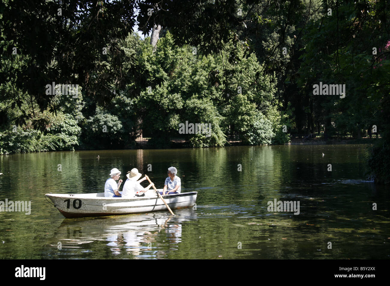 women in rowing boat on lake in villa park in rome italy Stock
