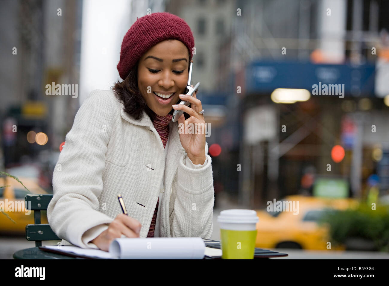 An attractive business woman talking on her cell phone while seated outdoors in the city Stock Photo