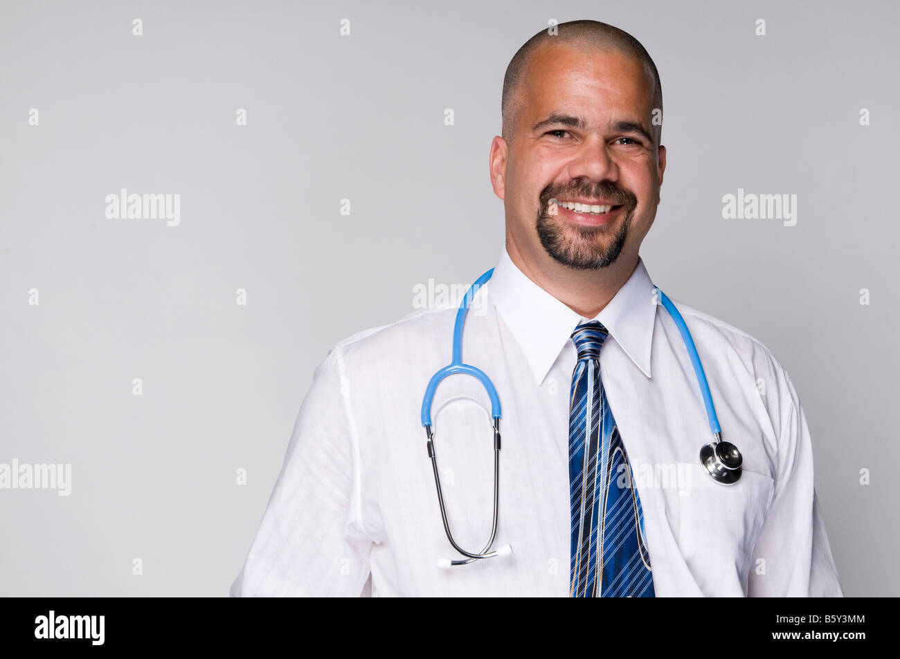 Friendly family doctor smiling with stethoscope in hospital Stock Photo