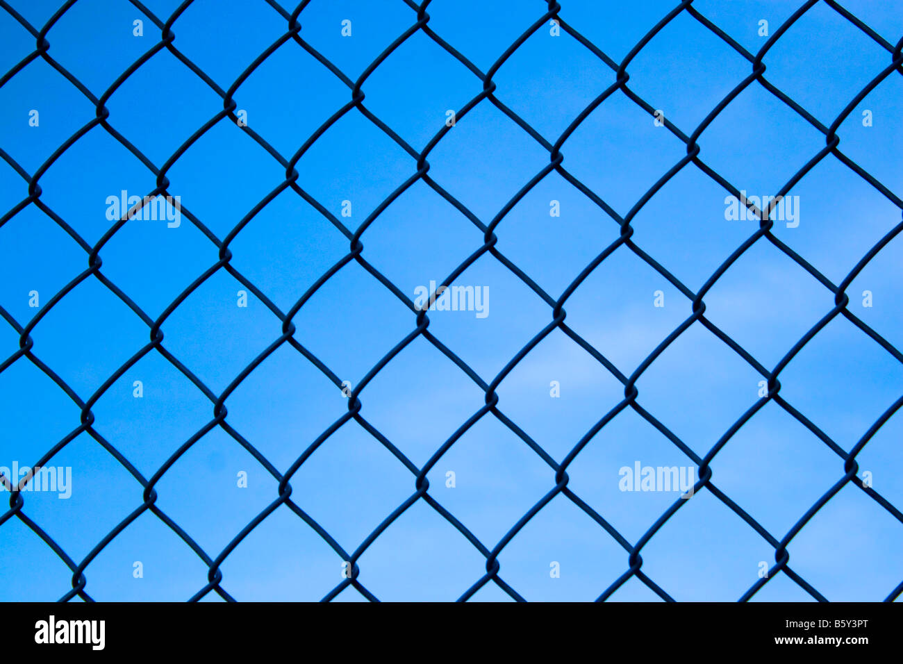 Closeup detail of a chain link fence over a blue sky Stock Photo