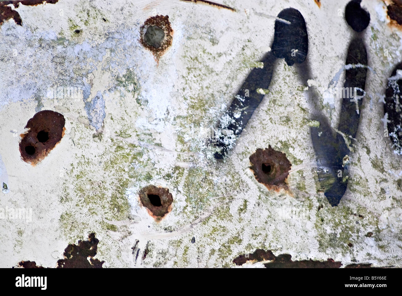 Closeup of rusted metal with chipped paint and bullet holes Stock Photo