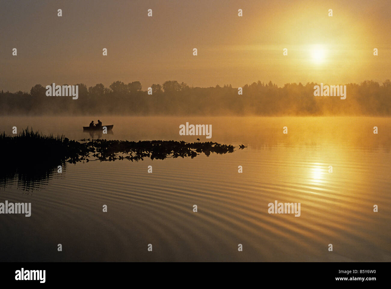 Sunrise at Lake Cassidy in fog with silhouetted fishermen in small