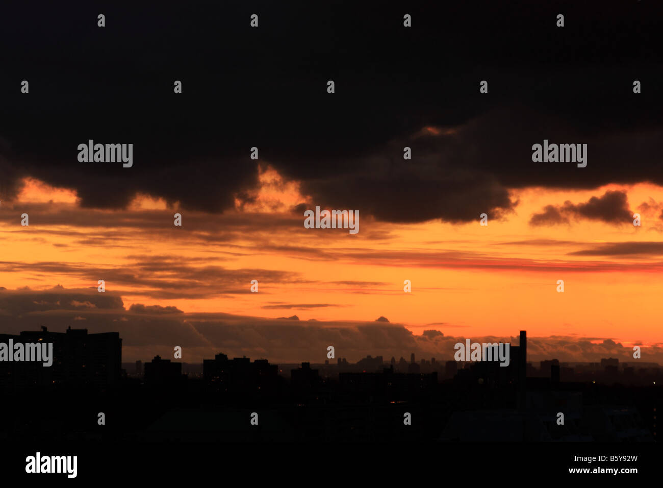 Sunset over silhouettes of west Toronto with dark threatening stratocumulus clouds associated with air mass behind cold front Stock Photo