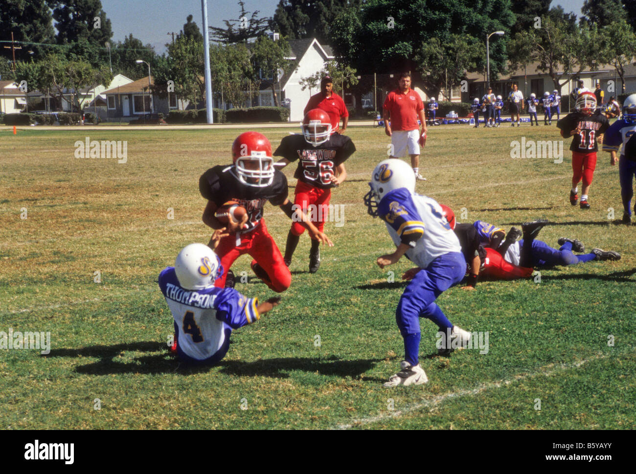 Young boys play little league football in city park. Stock Photo