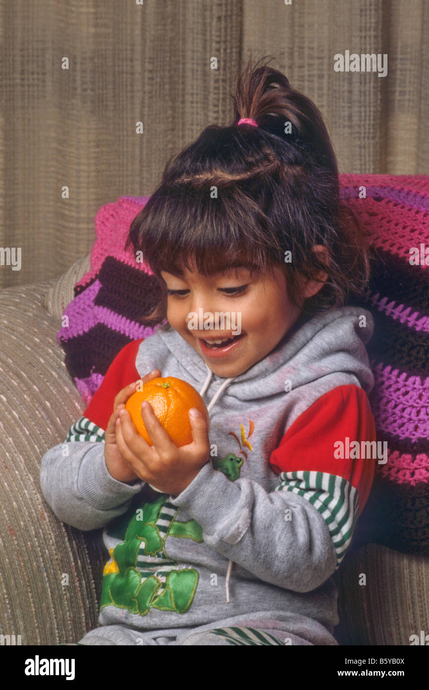 Hispanic toddler girl is excited to hold orange. Stock Photo