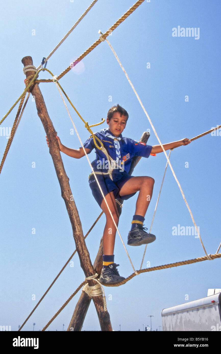 Cub scout boy walks on rope bridge erected by boy scouts at outdoor