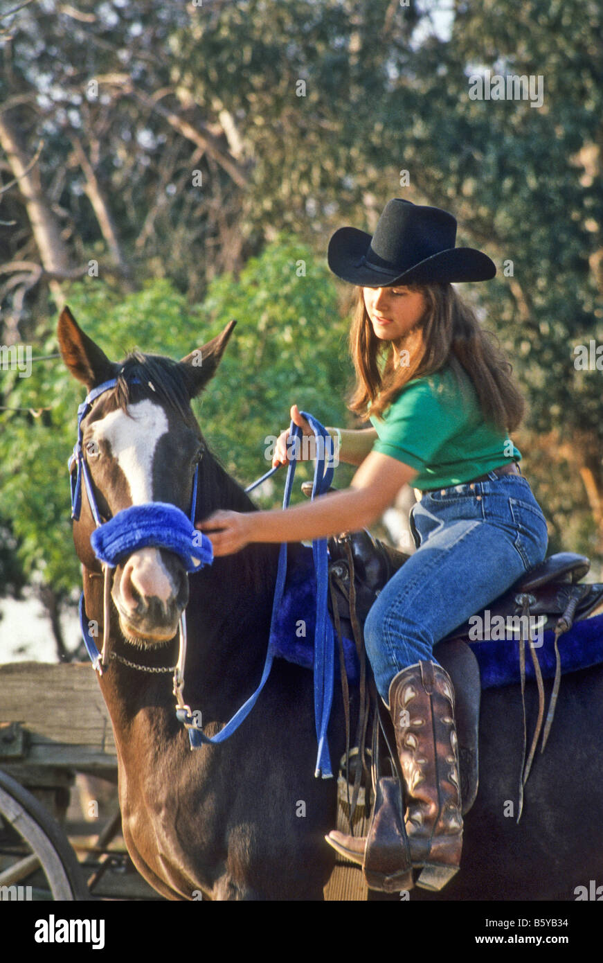 Teen girl in cowgirl clothes rides her horse Stock Photo