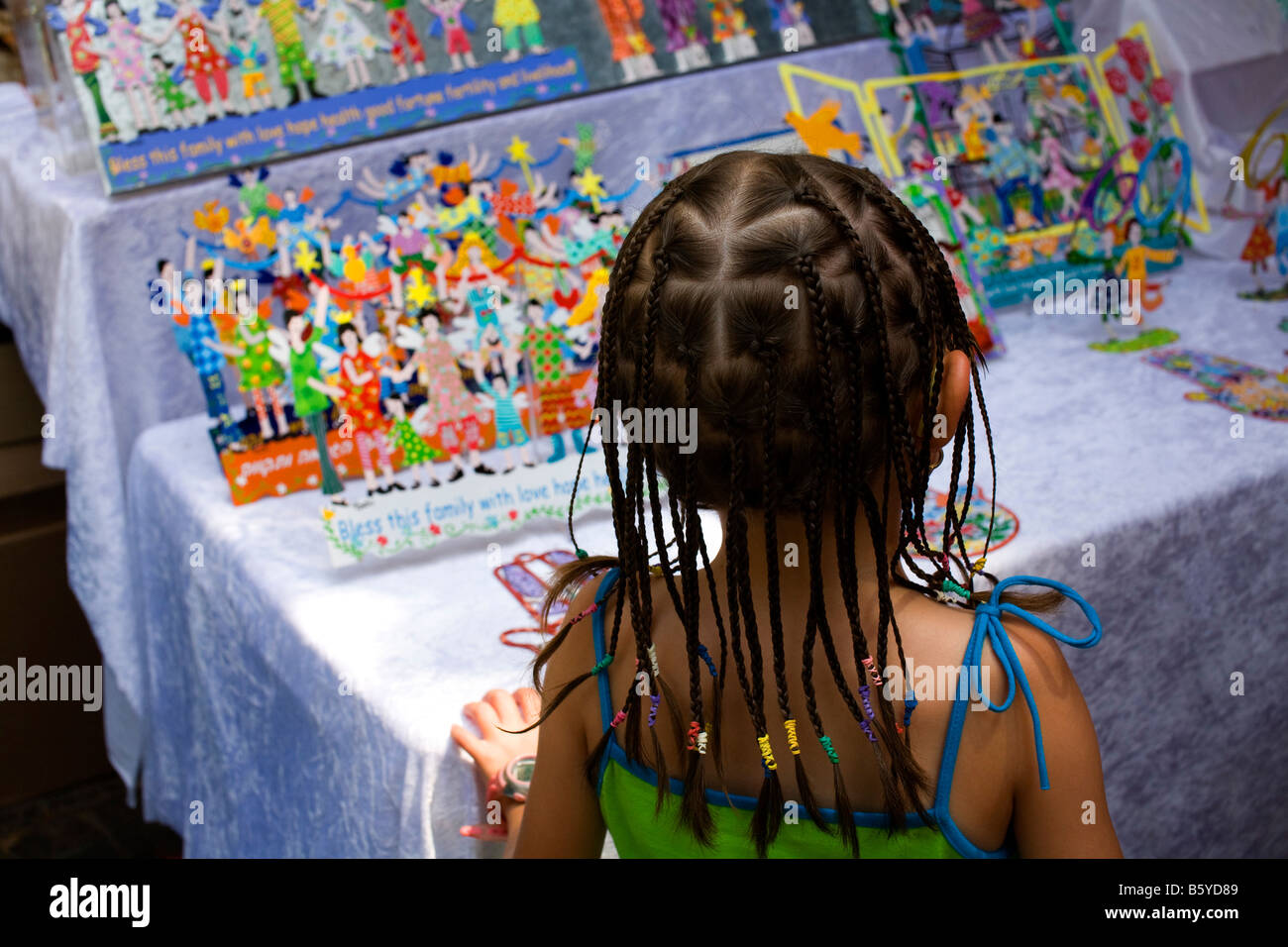 Young girl of four with plaited hair with back to camera looking at a toy display Stock Photo