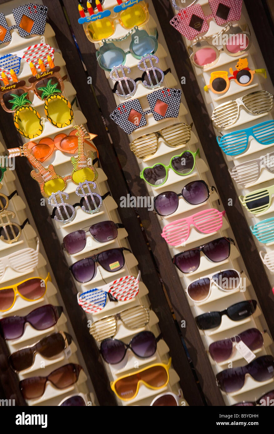 Humourous and colourful sunglasses for sale outside a beach shop. Stock Photo