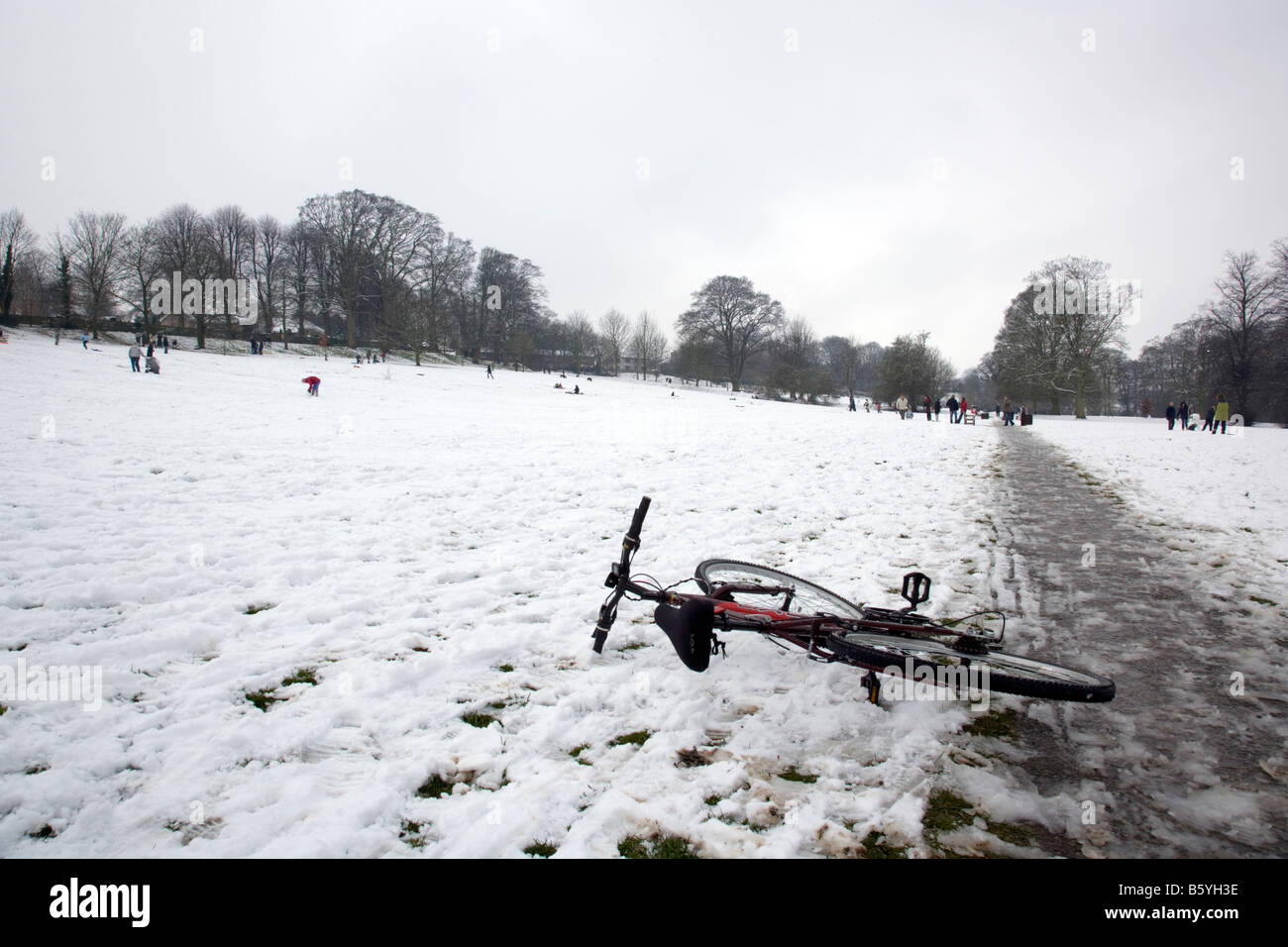 Push bike laying down abandoned in the snow in Westgate fields, Louth, Lincolnshire, England Stock Photo