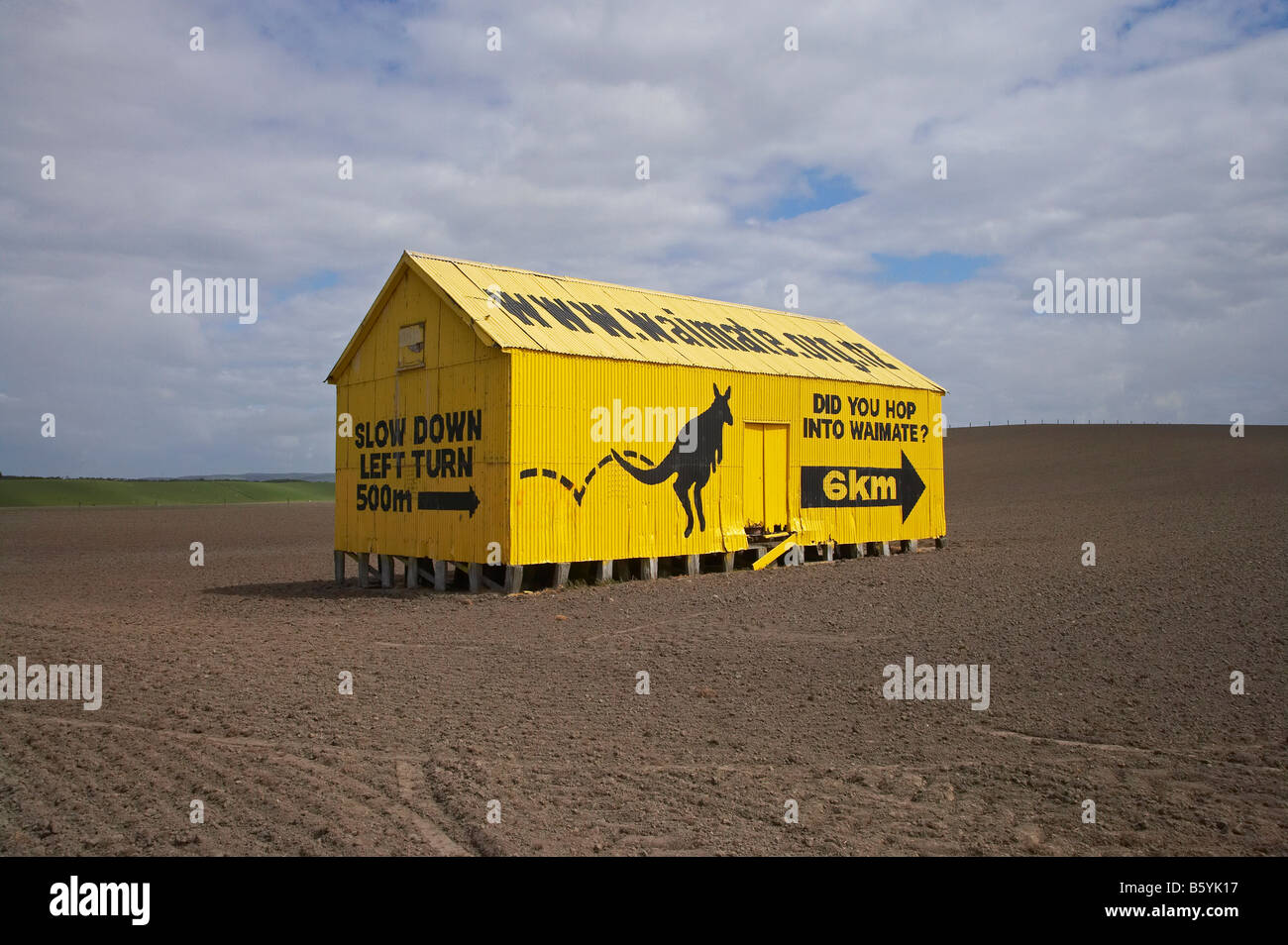 Sign to Waimate on Yellow Corrugated Iron Farm Shed State Highway One South Canterbury South Island New Zealand Stock Photo