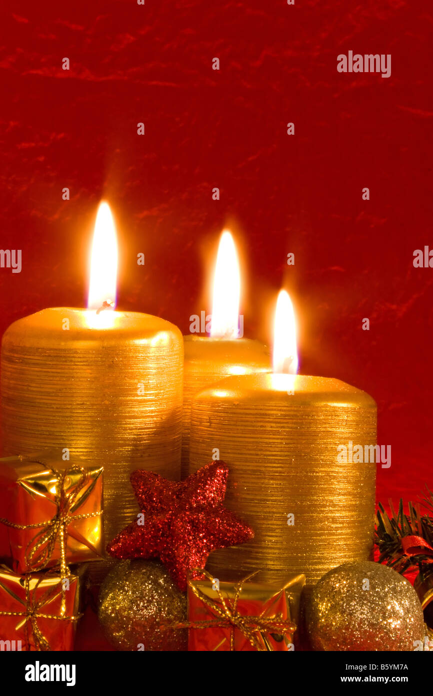 Three burning candles in a Christmas setting with seasonal decorations Stock Photo Alamy