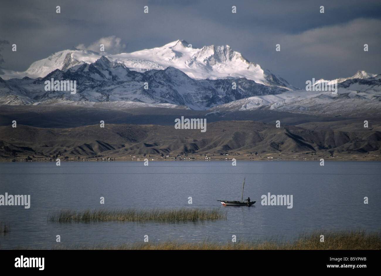 Small fishing boat, snowy peaks of the Cordillera Real mountain range in background, Lake Titicaca, Bolivia Stock Photo