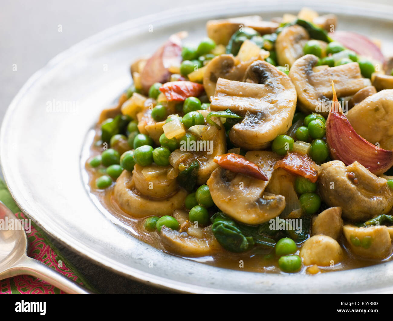 Mushroom and Pea Curry with Roasted Garlic on a Pewter Plate Stock