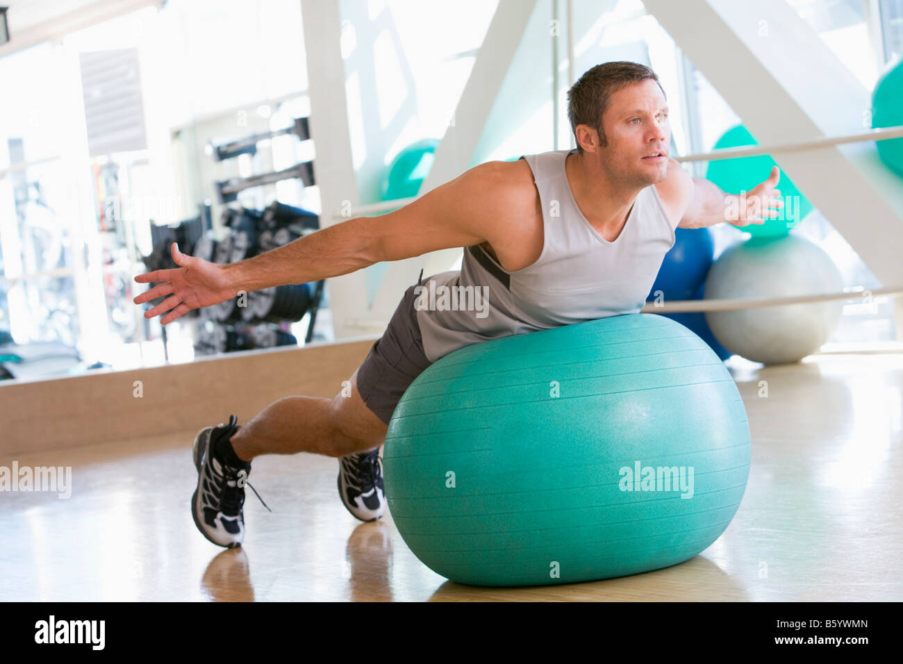 Man Balancing On Swiss Ball At Gym Stock Photo