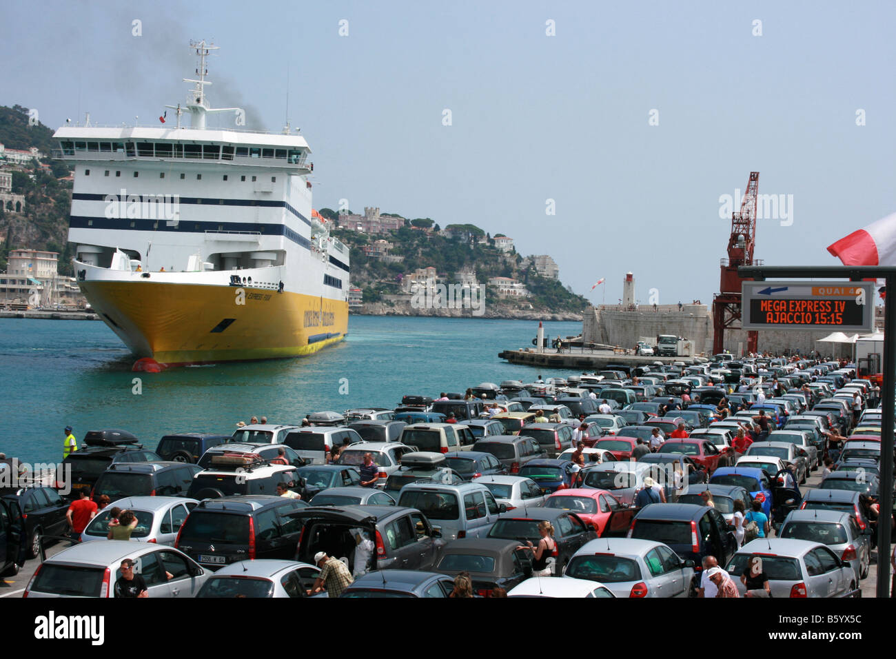 passengers on the dockside watch as Mega Express Four, the ferry from Corsica docks at the port of Nice, Côte d'Azur, France Stock Photo